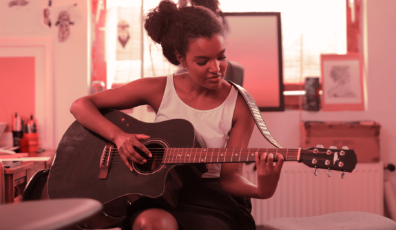Create your own music Woman playing guitar in living room