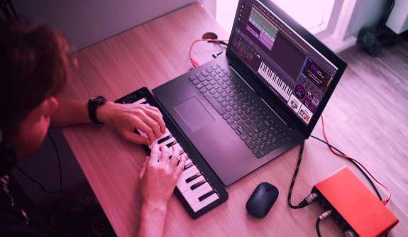Edit MIDI files Man sitting in front of a laptop and playing on mini keyboard